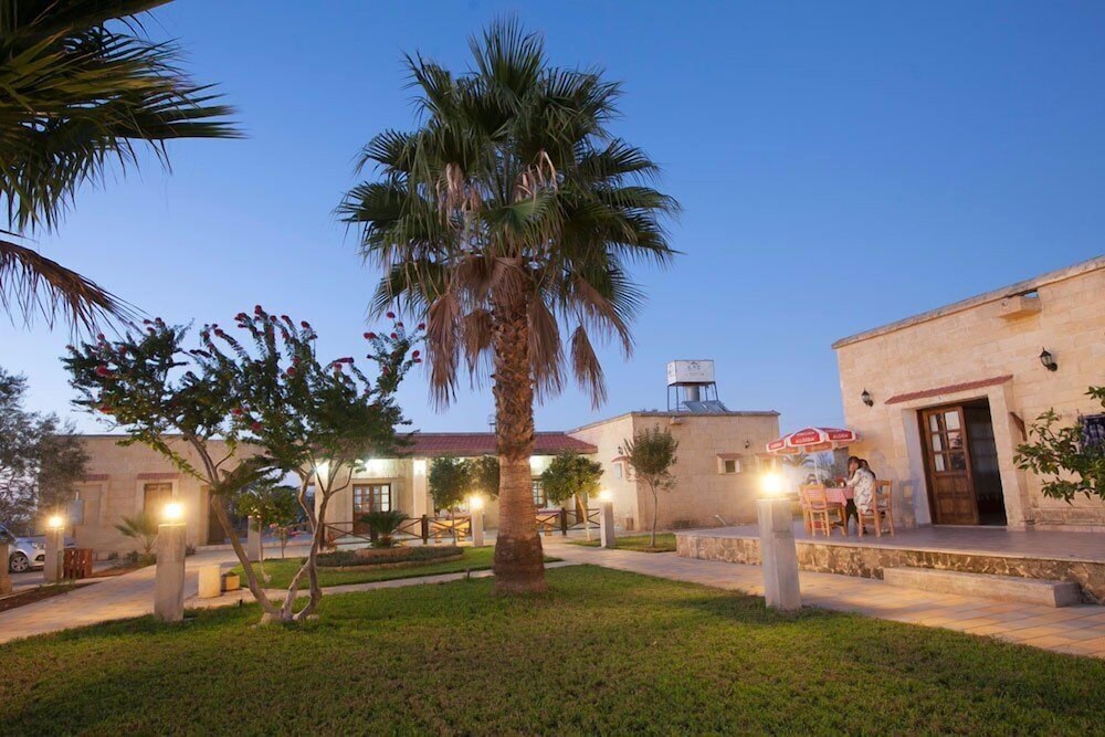 glaro garden hotel kıbrıs131 Akşamüstü bahçeli taş ev ve palmiye ağaçları.